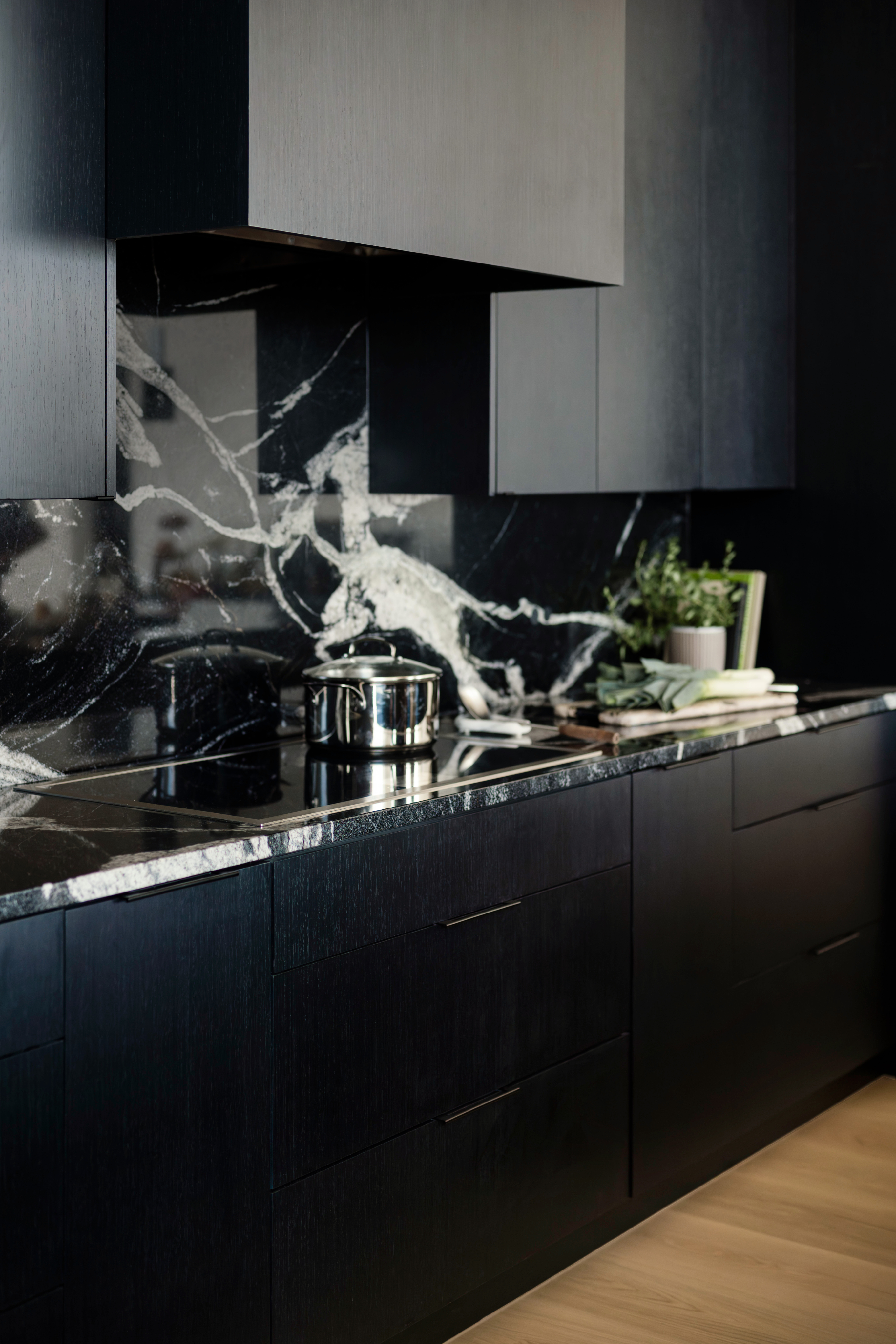 Custom black flat-panel cabinetry with marble waterfall island