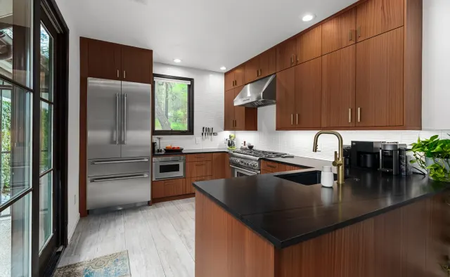 Annie Street Residence: Mid-century walnut flat-panel, U-shaped compact layout, black countertops, white backsplash, brushed-gold fixtures — view 1