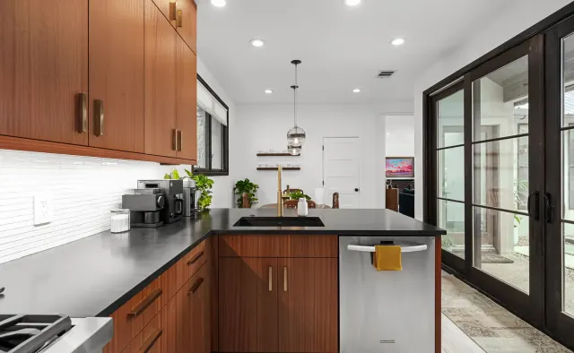 Annie Street Residence: Mid-century walnut flat-panel, U-shaped compact layout, black countertops, white backsplash, brushed-gold fixtures — view 2