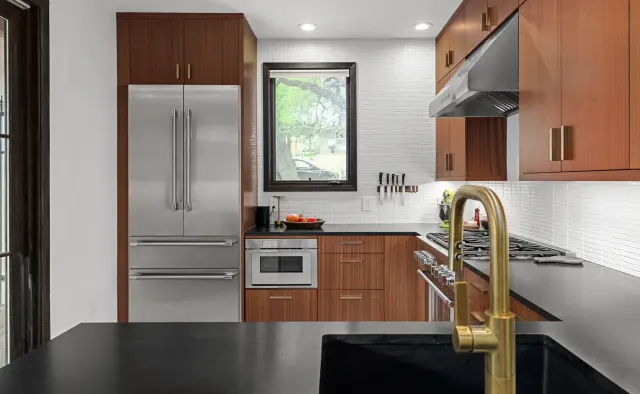 Annie Street Residence: Mid-century walnut flat-panel, U-shaped compact layout, black countertops, white backsplash, brushed-gold fixtures — view 4