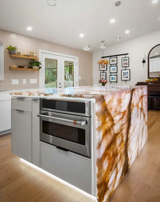 Cupid Residence: White flat-panel handleless cabinetry, rose-quartz waterfall island focal point, integrated lighting, floor-to-ceiling storage under vaulted ceiling — view 1