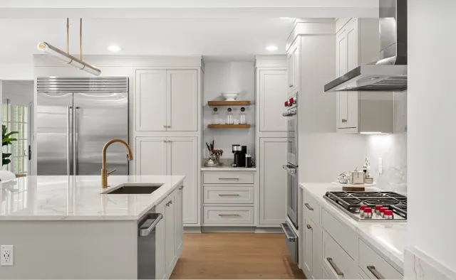 Eastledge Residence: Dove-gray shaker, marble island + backsplash, brass fixtures and barstools, warm wood floors — view 2