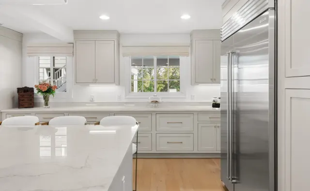 Eastledge Residence: Dove-gray shaker, marble island + backsplash, brass fixtures and barstools, warm wood floors — view 5