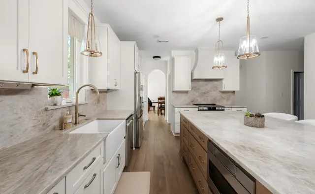 Falling Leaves Ct Residence: White perimeter + wood-stained island, large seating island, quartz counters, textured stone backsplash, open-concept — view 2