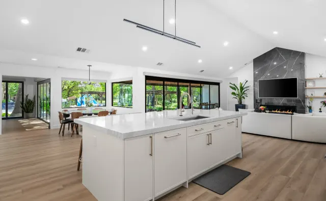 McNeil Dr Residence: White shaker under vaulted ceiling, marble island seating six, full marble backsplash, waterfall edges, walnut barstools — view 2