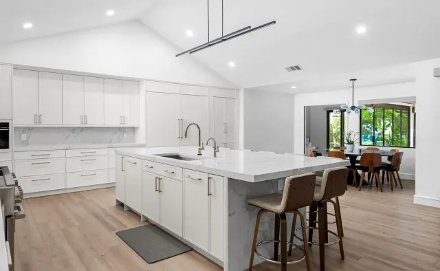 McNeil Dr Residence: White shaker under vaulted ceiling, marble island seating six, full marble backsplash, waterfall edges, walnut barstools — view 3