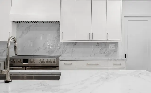 McNeil Dr Residence: White shaker under vaulted ceiling, marble island seating six, full marble backsplash, waterfall edges, walnut barstools — view 5