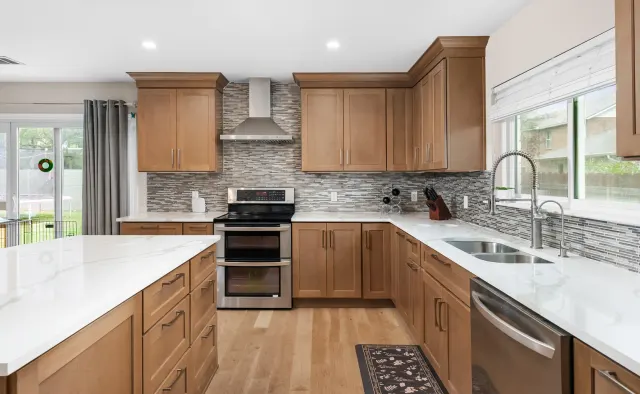 Petaluma Residence: Honey-toned shaker cabinetry, U-shaped layout, quartz countertops, linear glass-tile backsplash — view 1