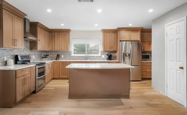 Petaluma Residence: Honey-toned shaker cabinetry, U-shaped layout, quartz countertops, linear glass-tile backsplash — view 2