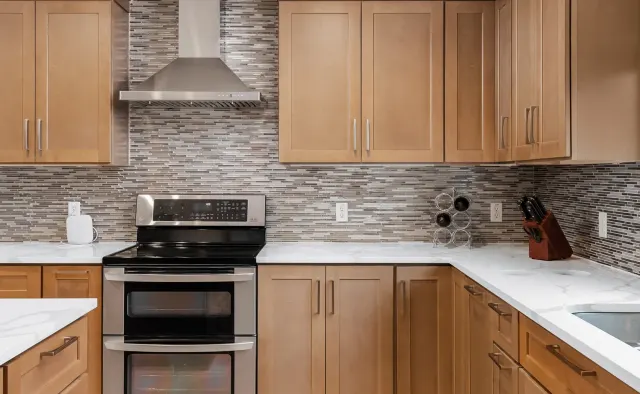 Petaluma Residence: Honey-toned shaker cabinetry, U-shaped layout, quartz countertops, linear glass-tile backsplash — view 3