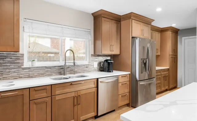 Petaluma Residence: Honey-toned shaker cabinetry, U-shaped layout, quartz countertops, linear glass-tile backsplash — view 4