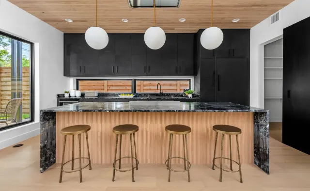 Southern Oaks Residence: Matte-black perimeter, fluted-wood island base, waterfall veined black stone island, reeded wood ceiling, brass accents — view 1