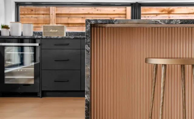 Southern Oaks Residence: Matte-black perimeter, fluted-wood island base, waterfall veined black stone island, reeded wood ceiling, brass accents — view 3